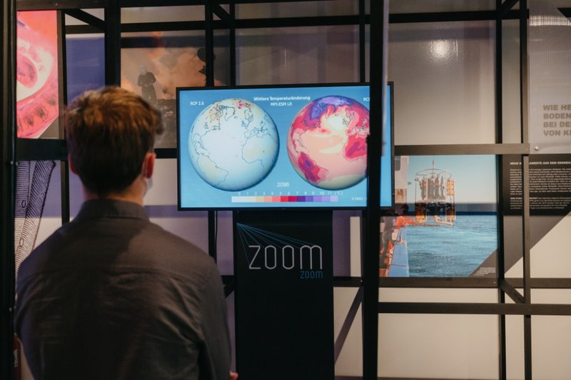 Ein Mann steht vor einem Bildschirm und betrachtet ein Bild der Erde und ihr Klima.